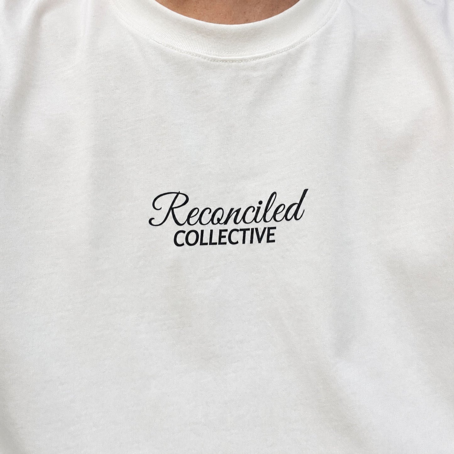 White t-shirt with 'Reconciled Collective' text on a plain background
