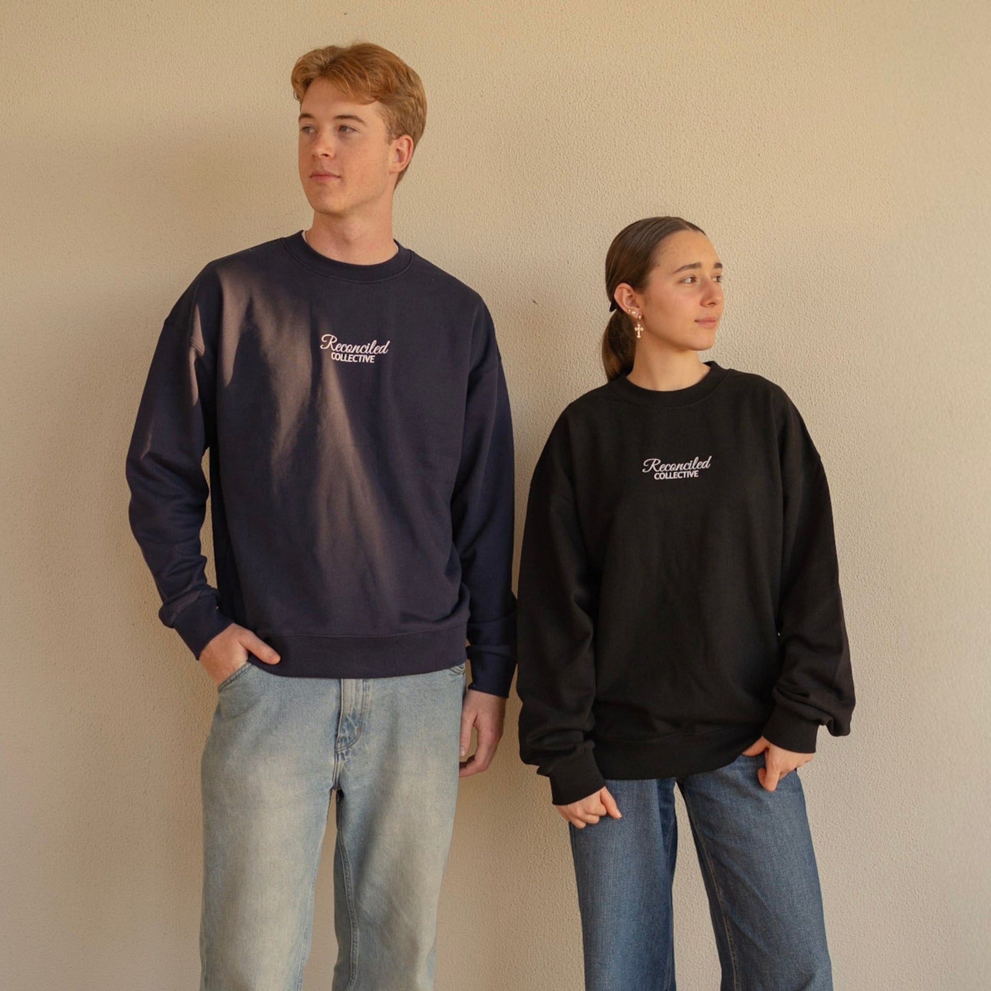 Two people wearing sweatshirts with a logo on a beige background