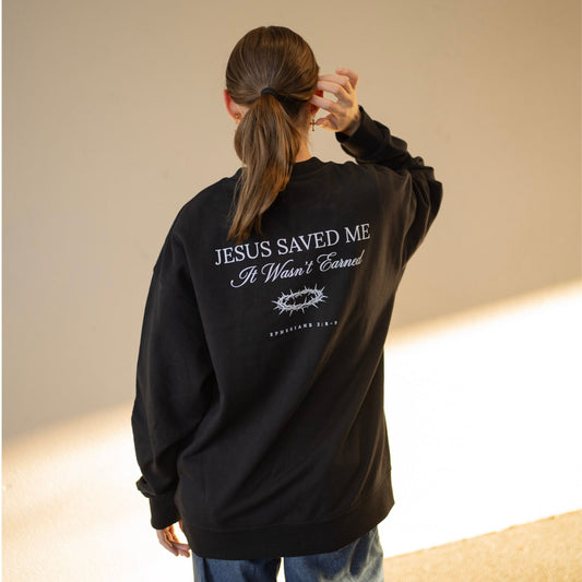 Person wearing a black sweatshirt with text on the back, standing against a neutral background.