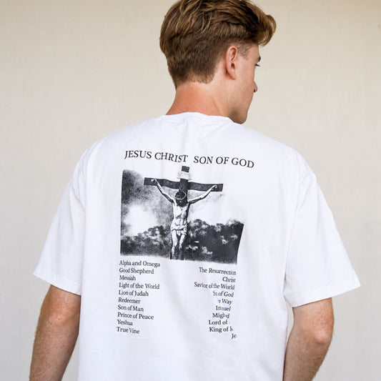 Person wearing a white t-shirt with a graphic and text on the back, standing against a plain background.