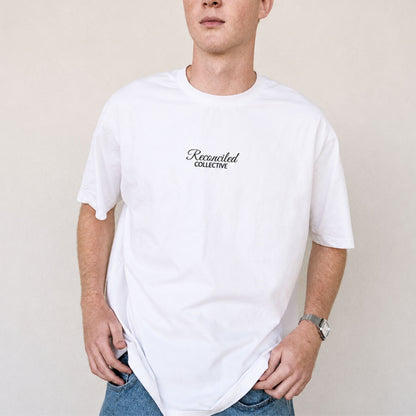 Person wearing a white t-shirt with 'Reconciled Collective' logo on a plain background