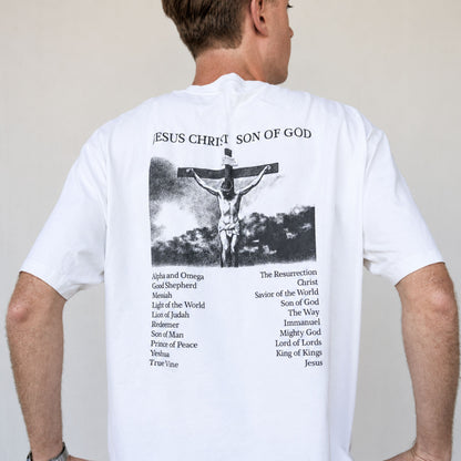 Model wearing a white Christian T-shirt featuring a Jesus Christ Son of God crucifixion back print with biblical names of Jesus listed underneath.